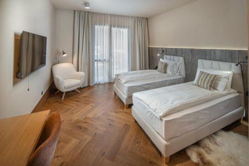a hotel room with two beds and a chair at Skigyimes Hotel in Lunca de Sus