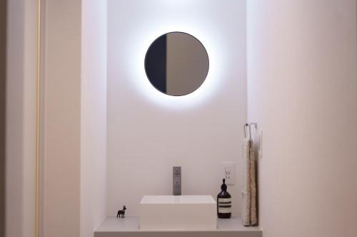 a mirror on a wall above a shelf with a bottle of wine at Star Seven Itoshima in Itoshima