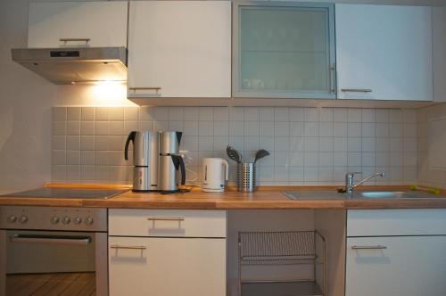 cocina con armarios blancos y encimera de madera en Linnen Luxx Apartment, en Berlín