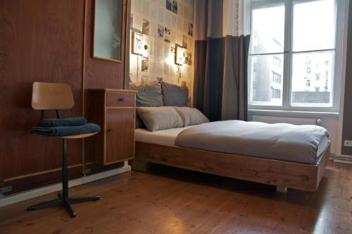 a bedroom with a bed and a chair and a window at Linnen Luxx Apartment in Berlin