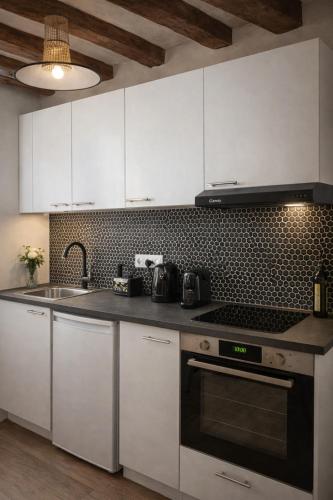 une cuisine avec des armoires blanches et une plaque de cuisson au four dans l'établissement Sweet Home, à Paris