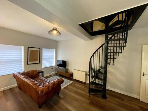 a living room with a couch and a spiral staircase at Central Industrial Chic 2-Bedroom Flat in Crewe