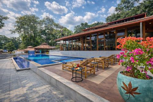a resort with a pool and tables and chairs at Regenta Resort Sakleshpur in Sakleshpur