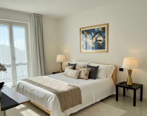 a white bedroom with a large bed and a window at Casa Ilaria in Armeno