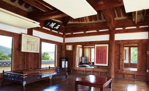 Großes Zimmer mit Holzwänden, Tischen und Fenstern in der Unterkunft Bukchondaek in Andong