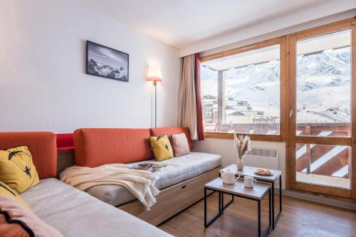 a living room with a couch and a large window at Résidence Pierre & Vacances Les Temples du Soleil in Val Thorens