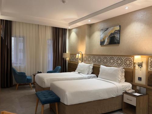 ein Hotelzimmer mit zwei Betten und einem Stuhl in der Unterkunft TIME Ruba Hotel & Suites in Mekka