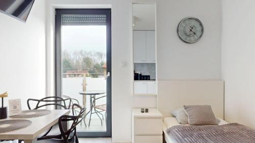 a room with a bed and a table and a clock at Apartament Fibra Bounty in Rybnik