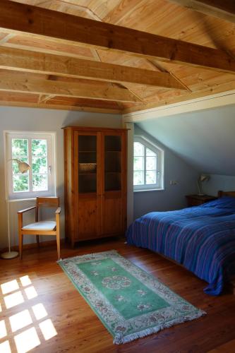 a bedroom with a bed and a chair and windows at Ferienhaus Malepartus Sächsische Schweiz in Bad Gottleuba
