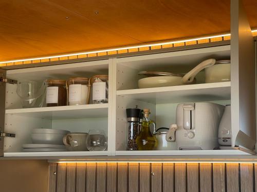 a kitchen cabinet filled with dishes and utensils at Barefoot Beach Hut in Skegness