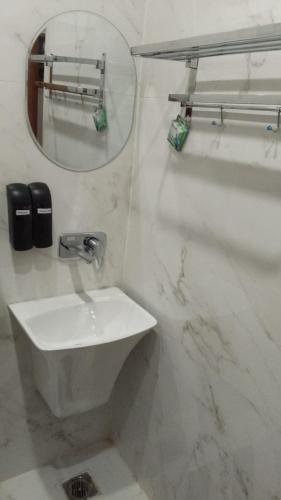ein weißes Badezimmer mit Waschbecken und Spiegel in der Unterkunft Hotel H Plus in Kurukshetra