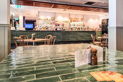 a restaurant with a table and chairs and a bar at Plantation Hotel Coffs Harbour in Coffs Harbour