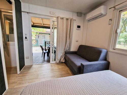 a bedroom with a bed and a couch and a patio at Villaggio Camping delle Rose - Gatteo a Mare in Gatteo a Mare