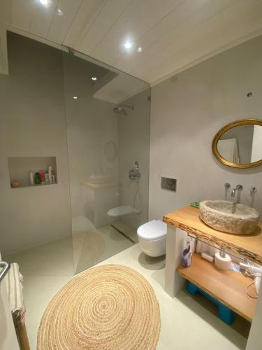 a bathroom with a sink and a toilet and a mirror at Pego Beach House in Grândola