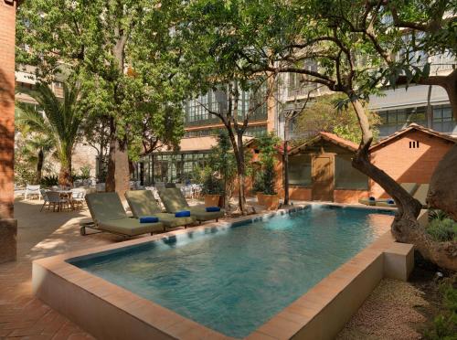 una piscina en un patio con sillas y árboles en H10 Casa Mimosa 4* Sup, en Barcelona