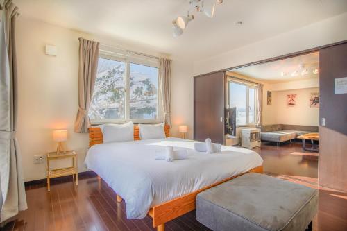 a bedroom with a large bed and a large window at North Furano House in Kami-furano
