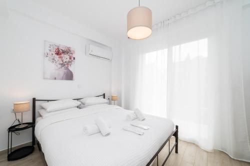 a white bedroom with a bed and a vase of flowers at Perla Stay Complex by Horizon Homes in Ofrínion