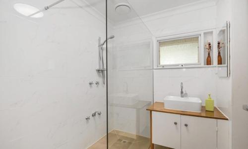 a white bathroom with a sink and a shower at Willows Cottage in Warburton