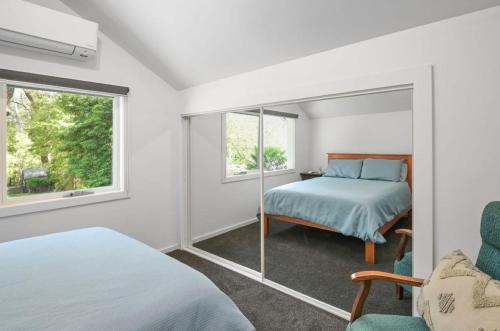 a bedroom with a bed and a mirror at Willows Cottage in Warburton
