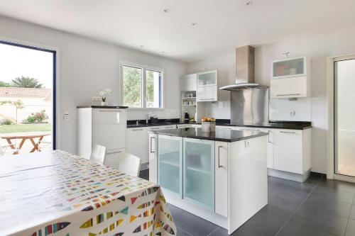 a kitchen with white cabinets and a table with chairs at Tour Maréchal - Villa d'Exception in LʼHerbergement