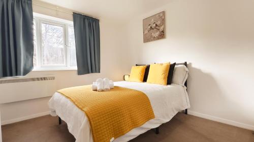 a bedroom with a bed with yellow sheets and a window at Colindale 4 bedroom house with garden and 2 parking spaces in Colindale