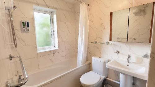 a bathroom with a sink and a toilet and a bath tub at Colindale 4 bedroom house with garden and 2 parking spaces in Colindale