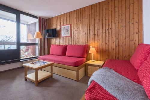 a room with two beds and a couch and a television at Résidence Pierre & Vacances Les Combes in Les Menuires