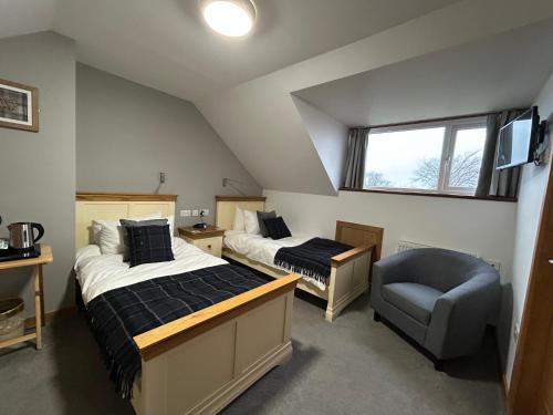 a attic bedroom with two beds and a chair at Karrawa Guest House in Kirkwall