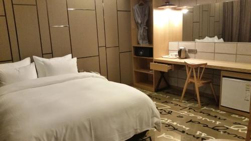 Habitación de hotel con cama blanca y escritorio en Kobos Hotel, en Seúl