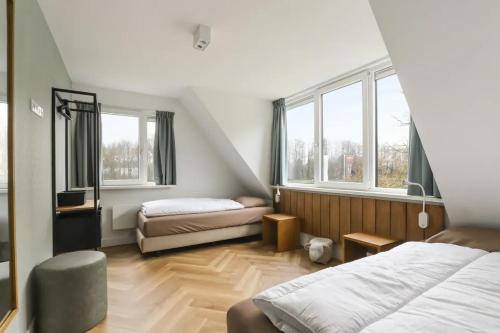 a bedroom with two beds and two windows at Villa Vechtrijk | 12 persons in Gramsbergen