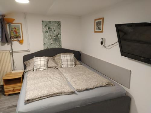 a bed with pillows and a television in a room at Agapé Mini Stúdió in Balatonalmádi