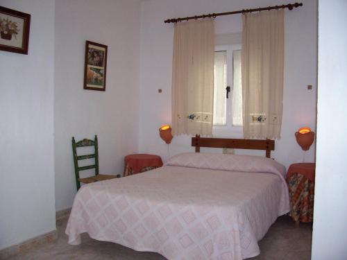 Castaño de RobledoにあるCasa Amigoのベッドと椅子2脚と窓のある寝室