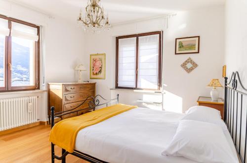 a white bedroom with a bed and a chandelier at Aosta Holiday Apartments - Edelweiss in Aosta