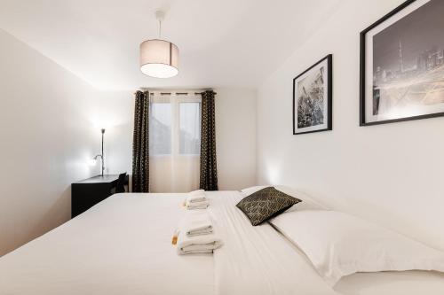 a bedroom with a white bed with towels on it at L'Horizon in Noisy-le-Grand