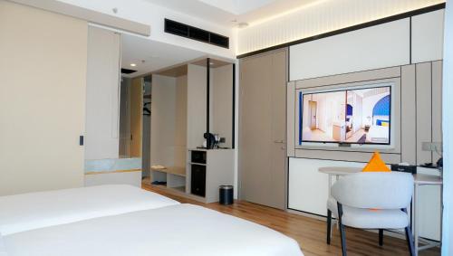 a bedroom with a white bed and a table and a chair at Nusatu by ARTOTEL - Semarang in Semarang