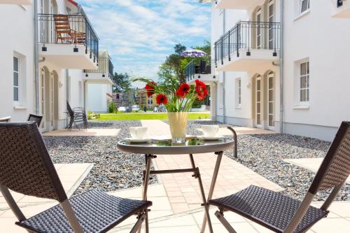 a patio with two chairs and a table with flowers at Meeresblick Fewo Strandnest - in Baabe