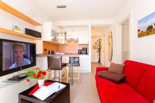 a living room with a red couch and a kitchen at Meeresblick Fewo Strandnest - in Baabe