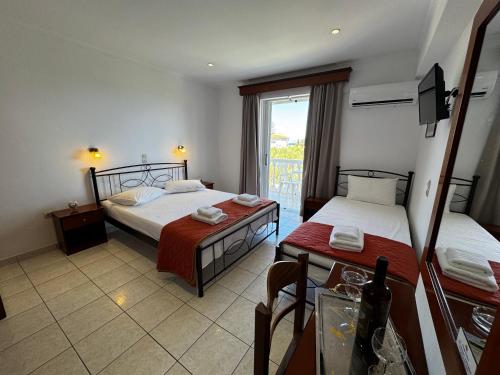 a room with two beds and a table and a window at Pelagos Studios in Amoudi
