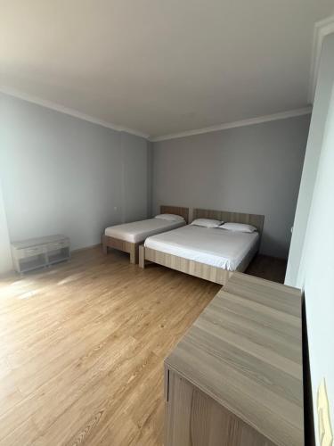 a room with two beds and a wooden floor at у моря in Itʼkhvisi