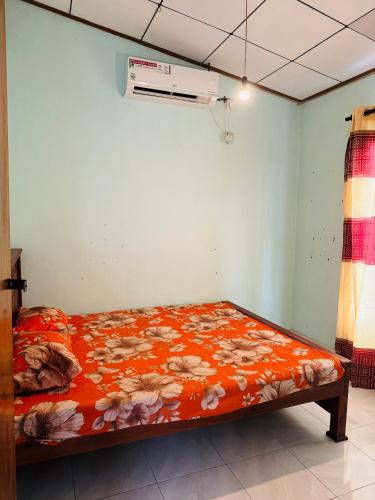 a bed in a room with an orange blanket with flowers at Matara Villa in Matara
