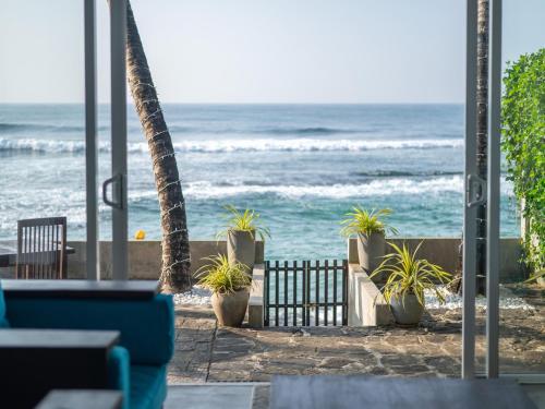 a view of the ocean from a restaurant with plants at Florain Otium Talpe in Unawatuna