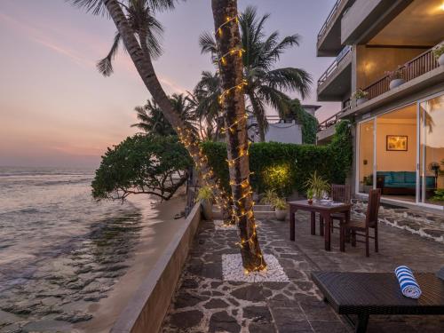 a resort patio with a table and chairs and the ocean at Florain Otium Talpe in Unawatuna