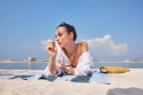 a woman laying on the sand on the beach at SO Ras Al Khaimah Hotel & Resort-Ultra All Inclusive in Ras al Khaimah