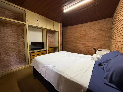 a bedroom with a large bed and a television at Quarto confortável no Centro in Botucatu