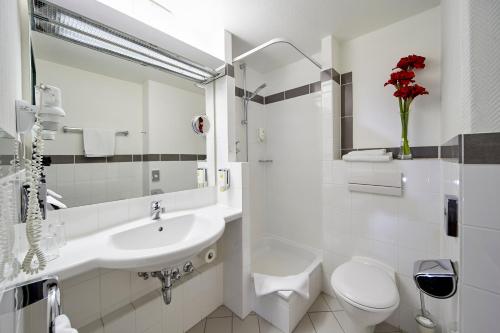 a white bathroom with a sink and a toilet at Balance Hotel Leipzig Alte Messe in Leipzig