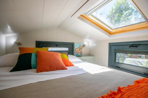 a bedroom with a bed with colorful pillows and a window at Procida Camp & Resort - La Caravella in Procida