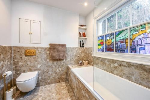 a bathroom with a tub and a toilet and a window at Hastings View in Hastings
