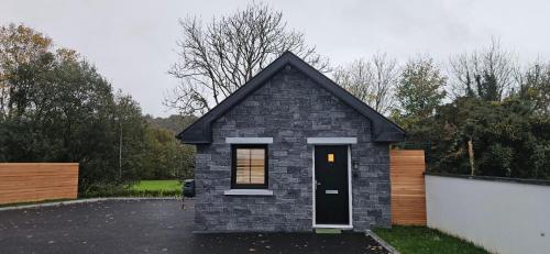 a small house with a black door in a parking lot at Sullane Weirs in Macroom