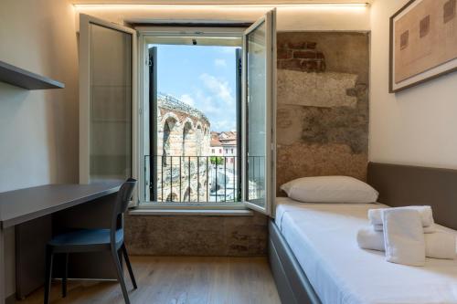 a room with a bed and a desk and a window at Residenza Wega - Luxury Apartments Verona in Verona