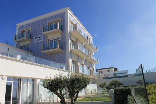 a building with a blue facade with a tree in front at Ocean View Apartments in Lourinhã